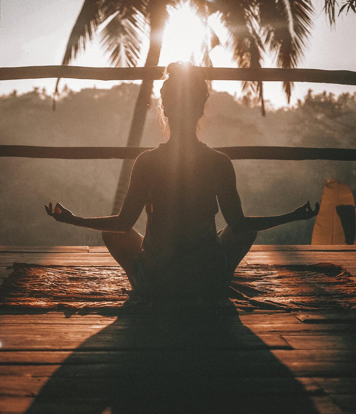 A person meditating at sunrise