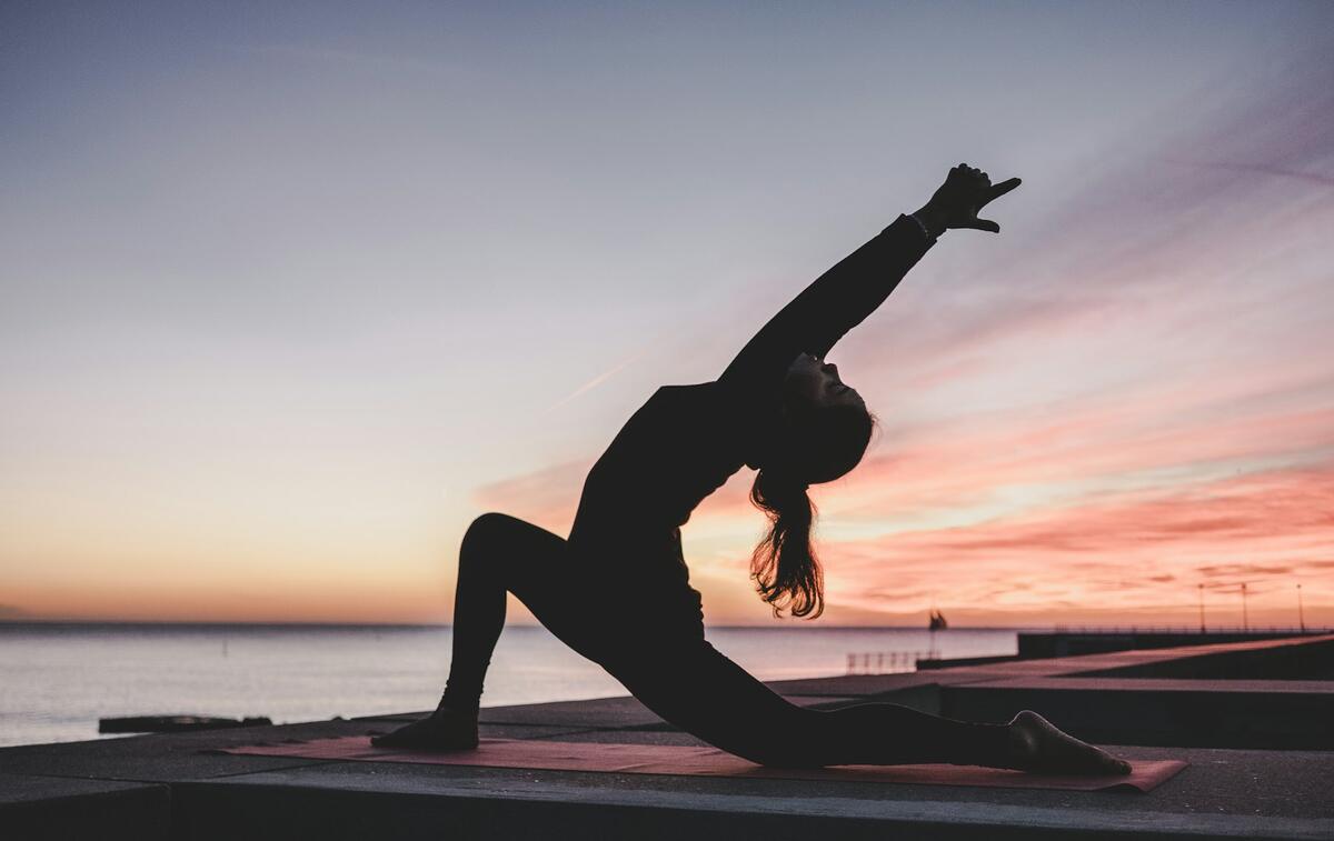 A woman stretching at sunset